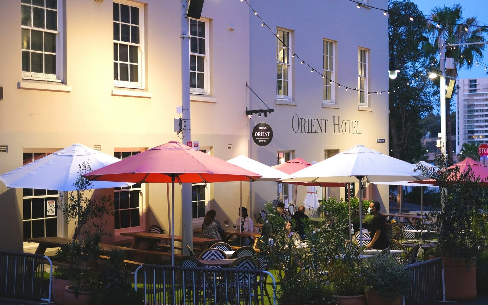 Tables under umbrellas on a restaurant strip. Surry Hills' weekend demand comes from its own streets rather than from a season or an event calendar.