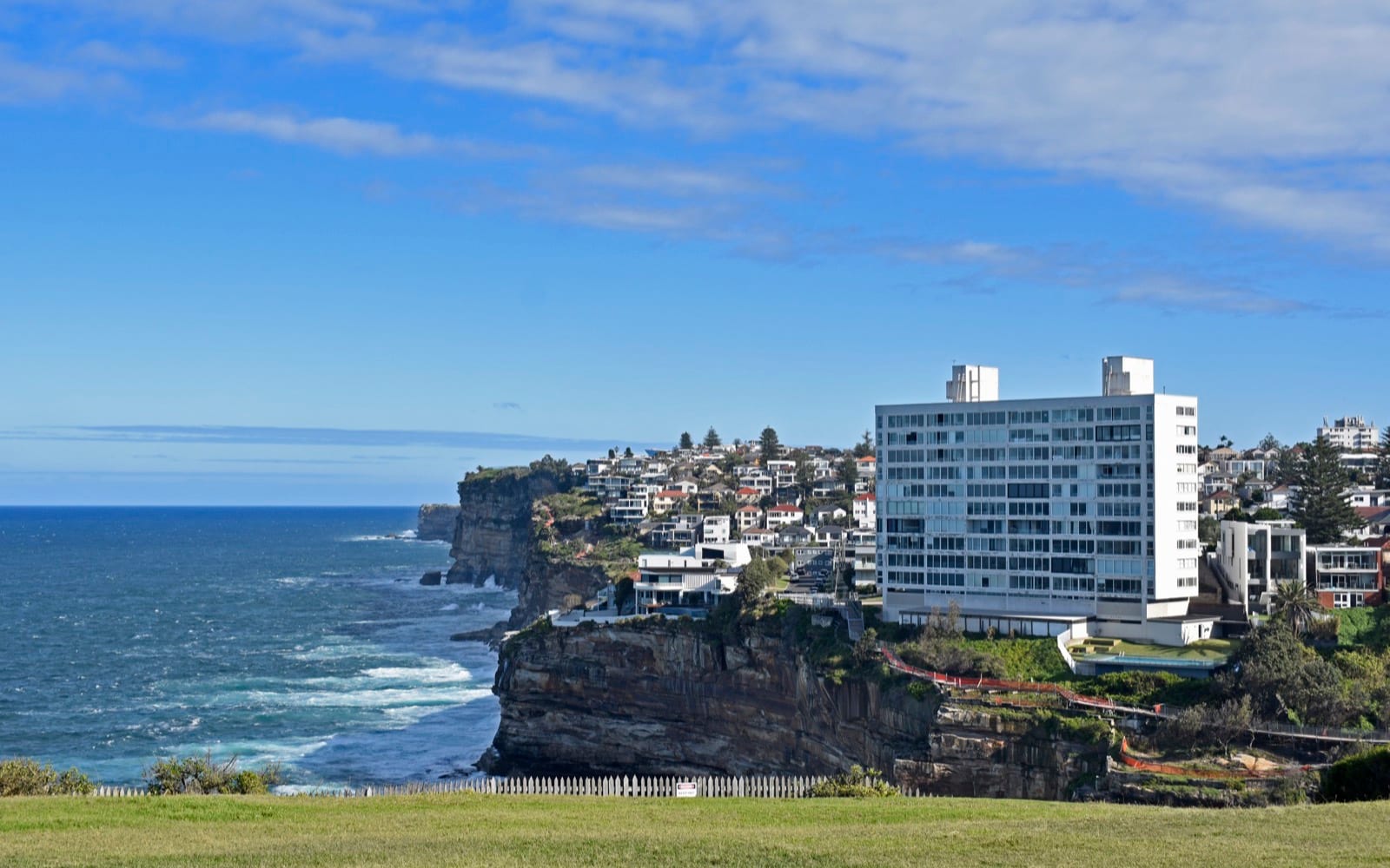 The sandstone clifftop at Vaucluse, houses and an apartment tower along the edge above the open sea.